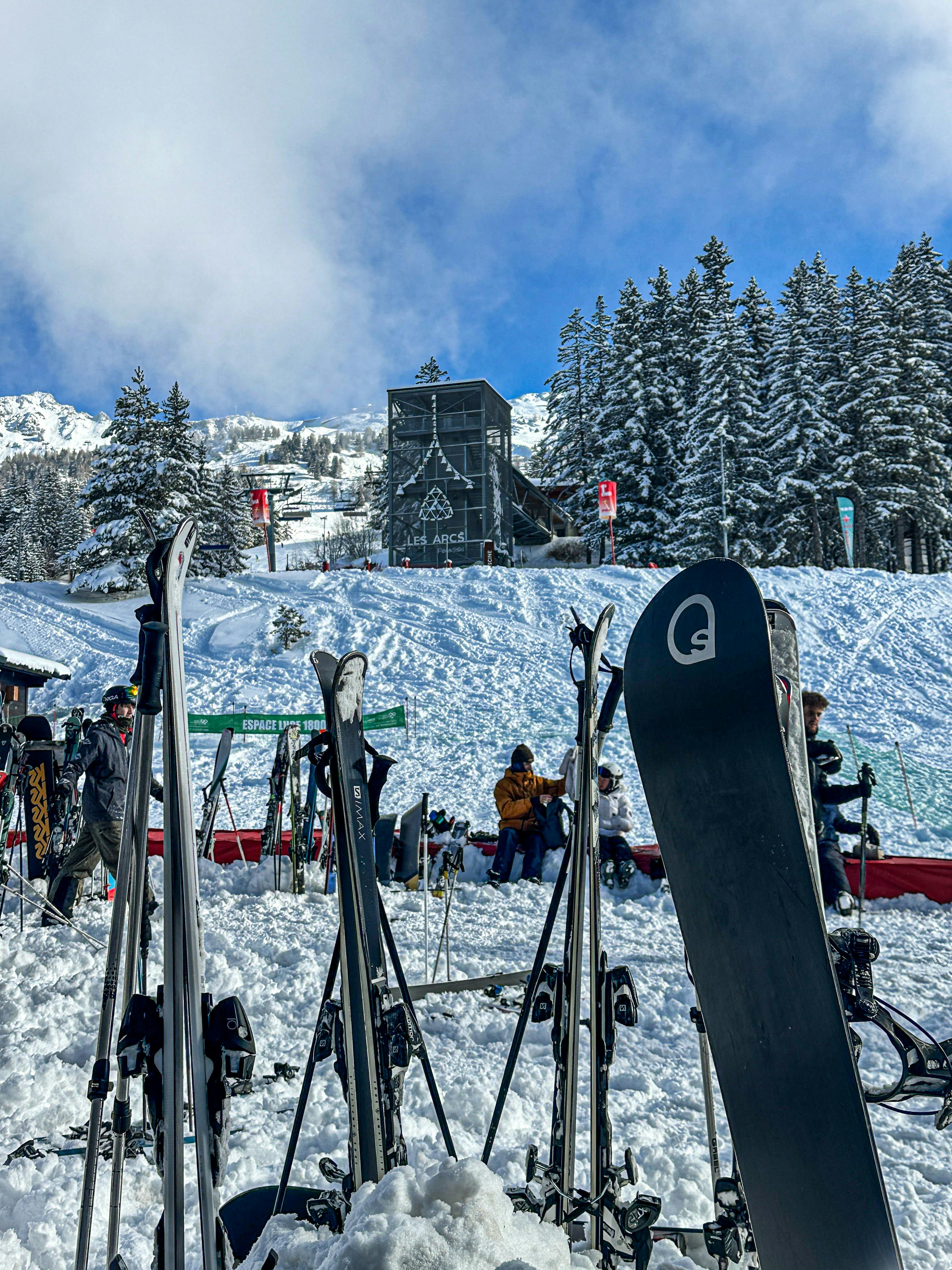 Skiers and snowboarders preparing equipment near a lift station at Les Arcs ski resort in the French Alps
